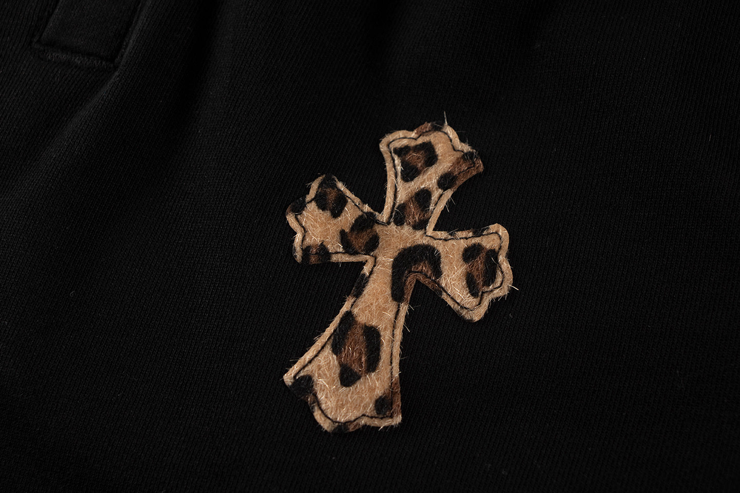 Embroidered cross applique on black shorts fabric