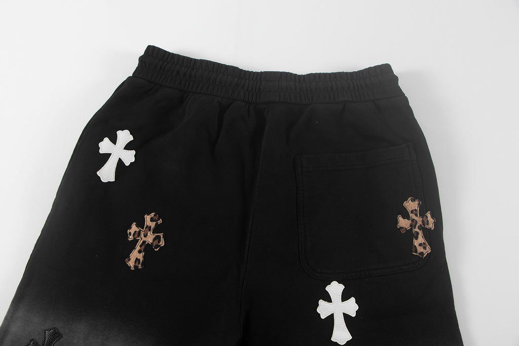 Black shorts with elastic waistband, side pocket, and cross appliques