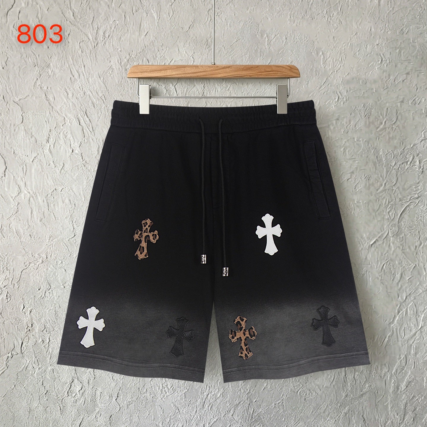 Black shorts with drawstring and scattered cross appliques, front view