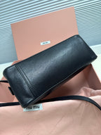Black leather mini handbag with long shoulder strap and front stitched panel.