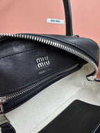 Black leather handbag interior close-up with embossed logo and silver zipper track.