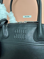 Black leather MiuMiu handbag with embossed logo on front and stitched handle base