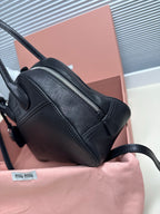 Black leather MiuMiu mini bag with side seams, top zipper and crossbody strap