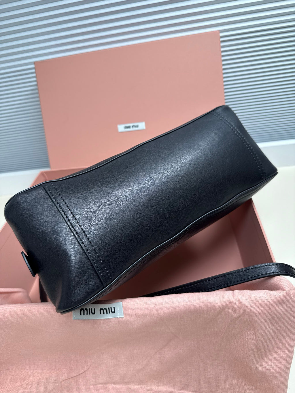 Black leather MiuMiu mini bag with structured shape, zipper top and shoulder strap