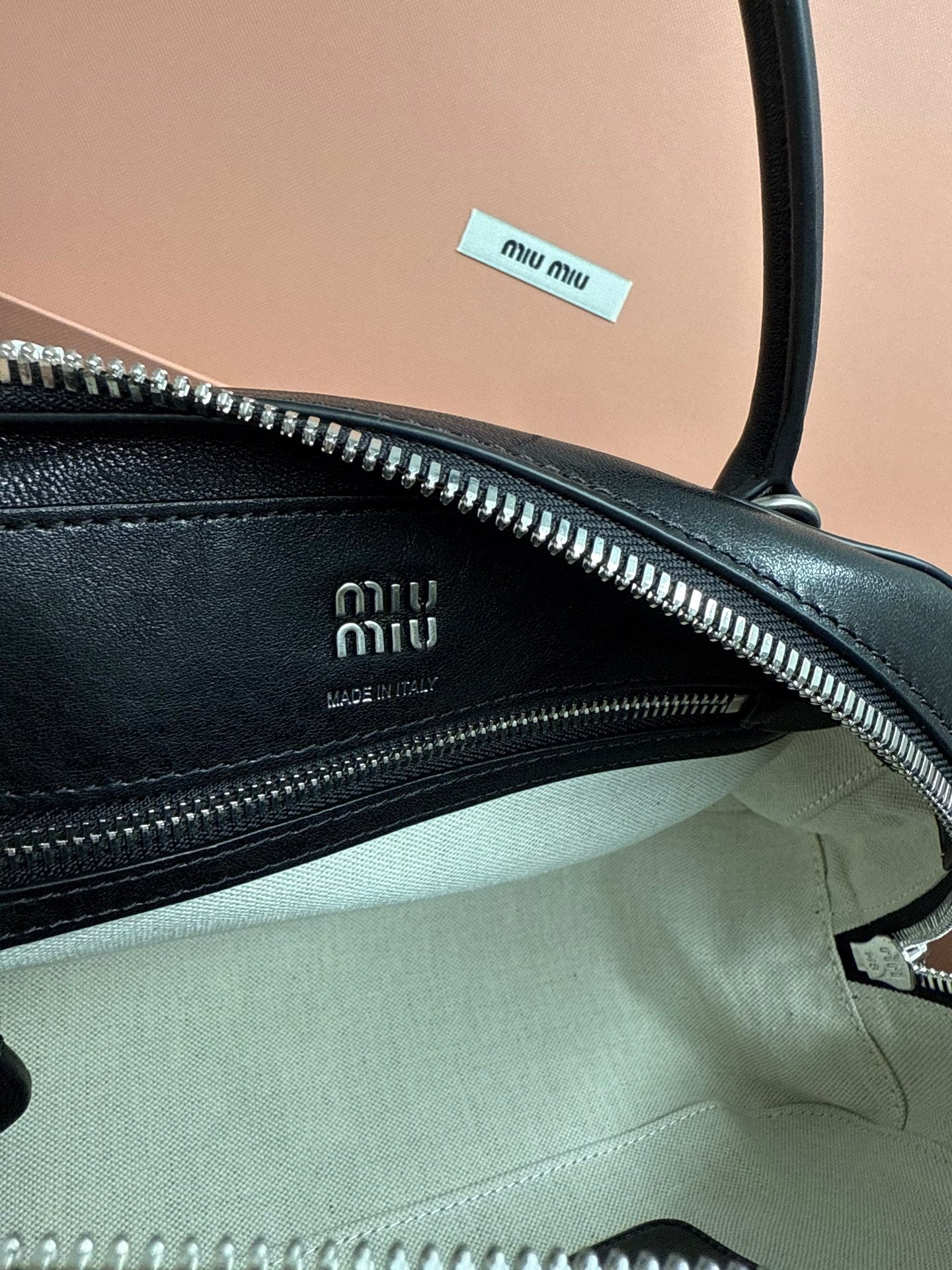 Black leather MiuMiu bag with zipper track and fabric lining, interior logo