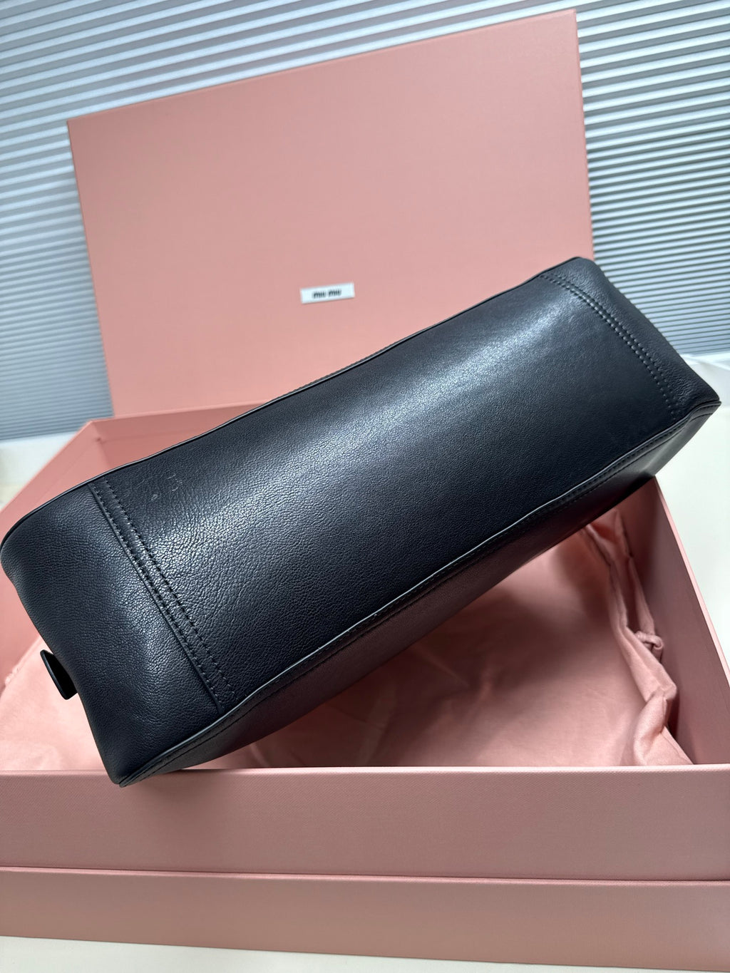 Dark green leather baguette bag with structured rounded silhouette and short handles.