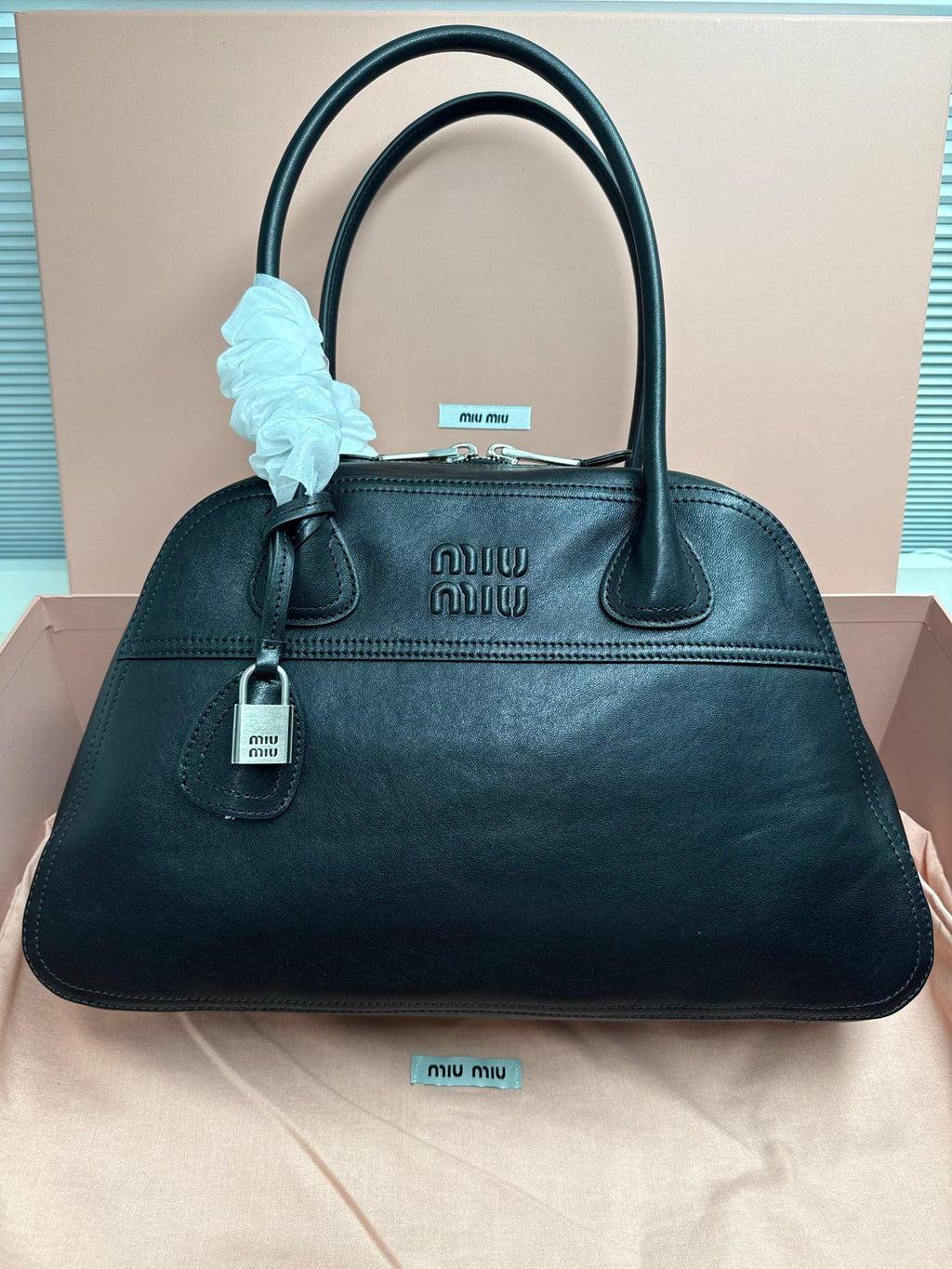 Dark green leather handbag with top handles and front logo plaque.