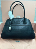 Dark green leather handbag with top handles and front logo plaque.