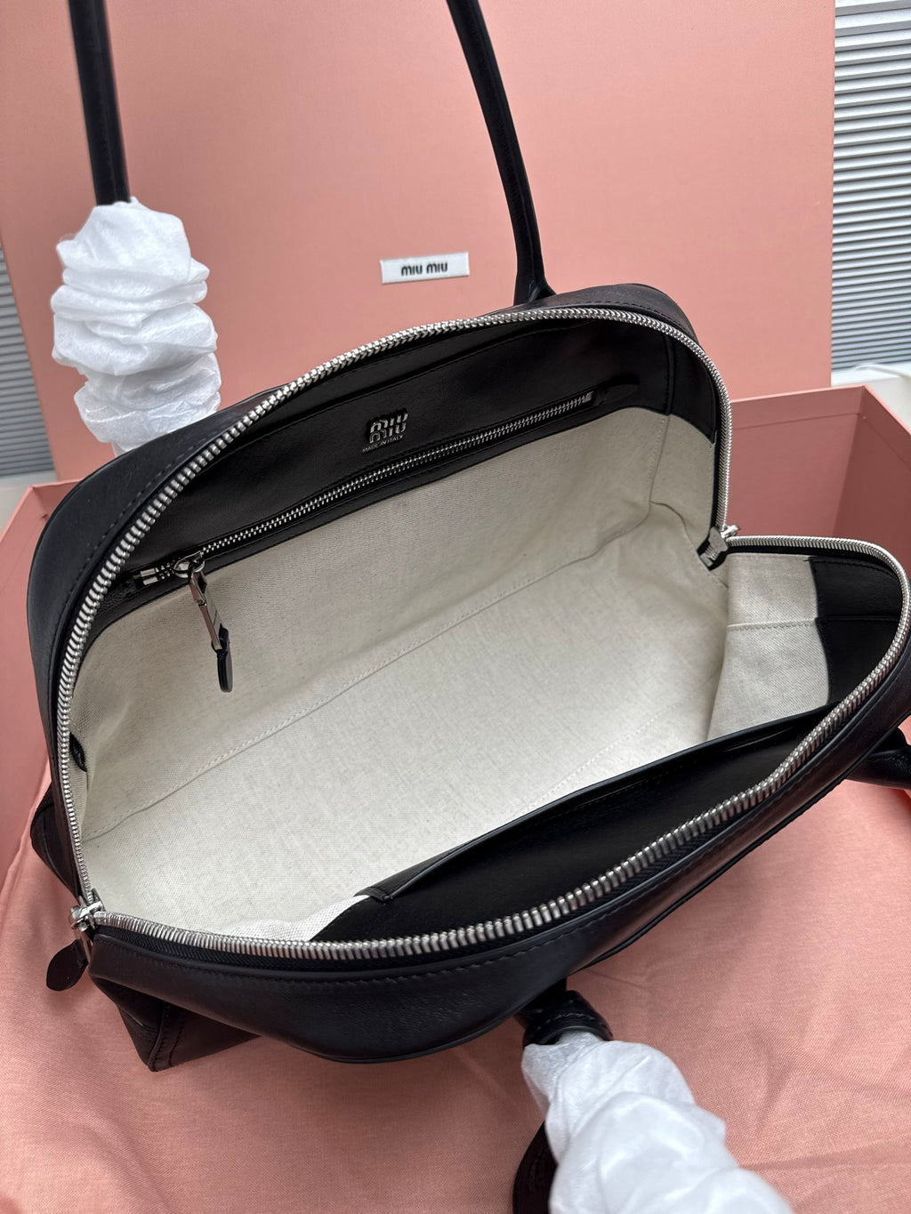 Dark green leather handbag opened to reveal beige fabric interior lining.