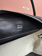 Beige interior of dark green leather bag with embossed Miu Miu logo and zipper.