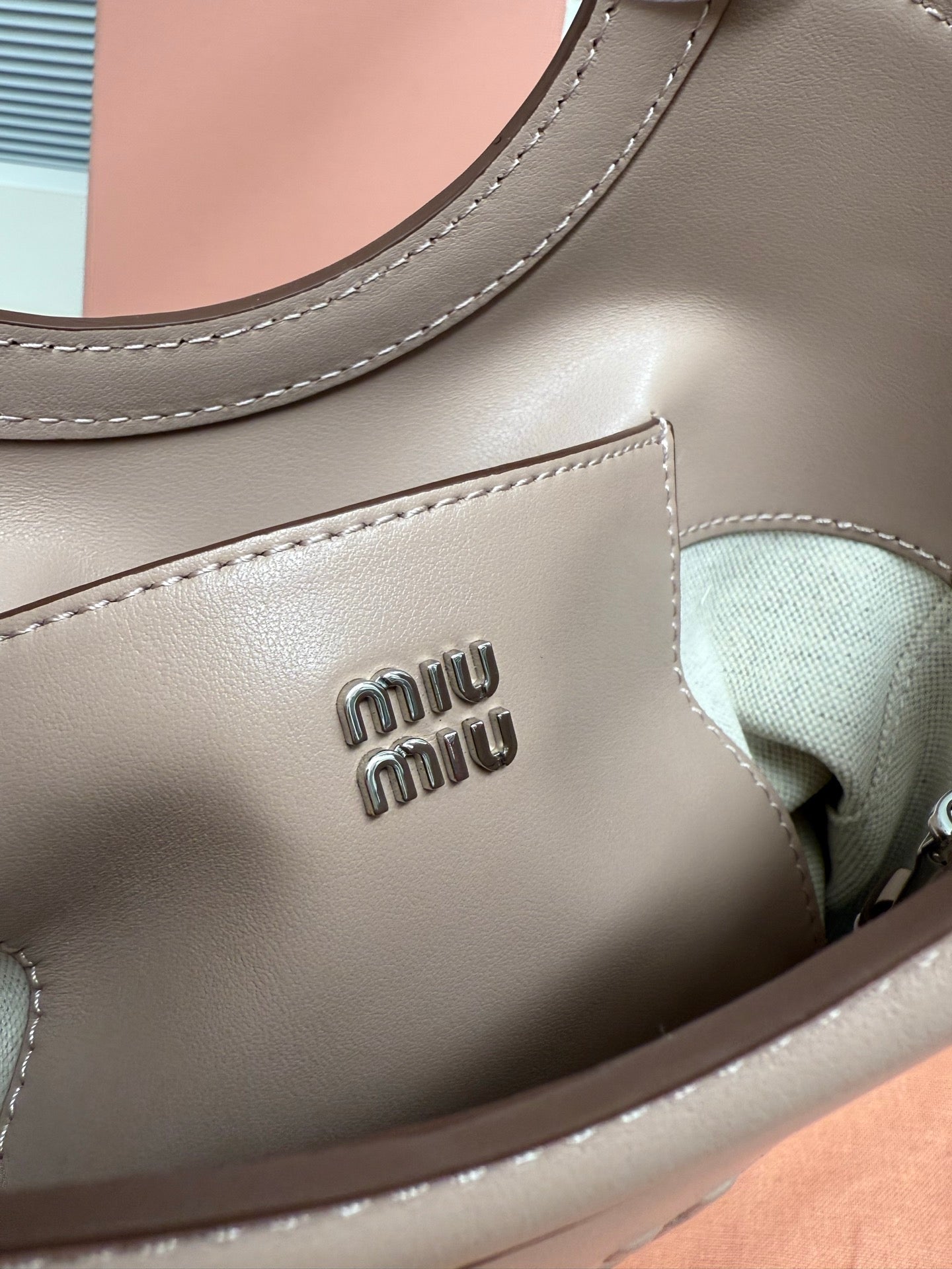 MiuMiu leather bag close-up with embossed “miu miu” logo and contrast stitching