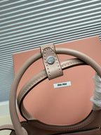 MiuMiu mini bag strap detail with stitched leather tab and light gray finish
