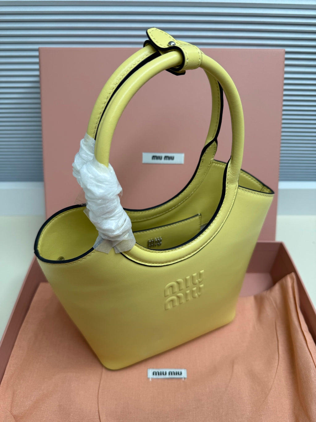 Lime green MiuMiu tote bag with top handle and white protective wrap