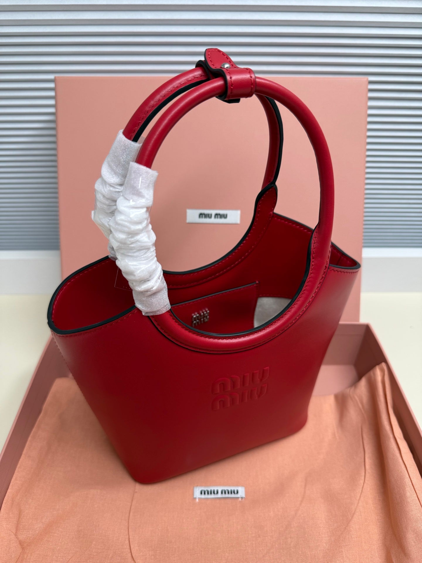 Red leather Miu Miu top-handle bag with wide strap and fabric-wrapped handle grip