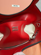 Red leather Miu Miu bag side with “miu miu” embossing and zipper hardware