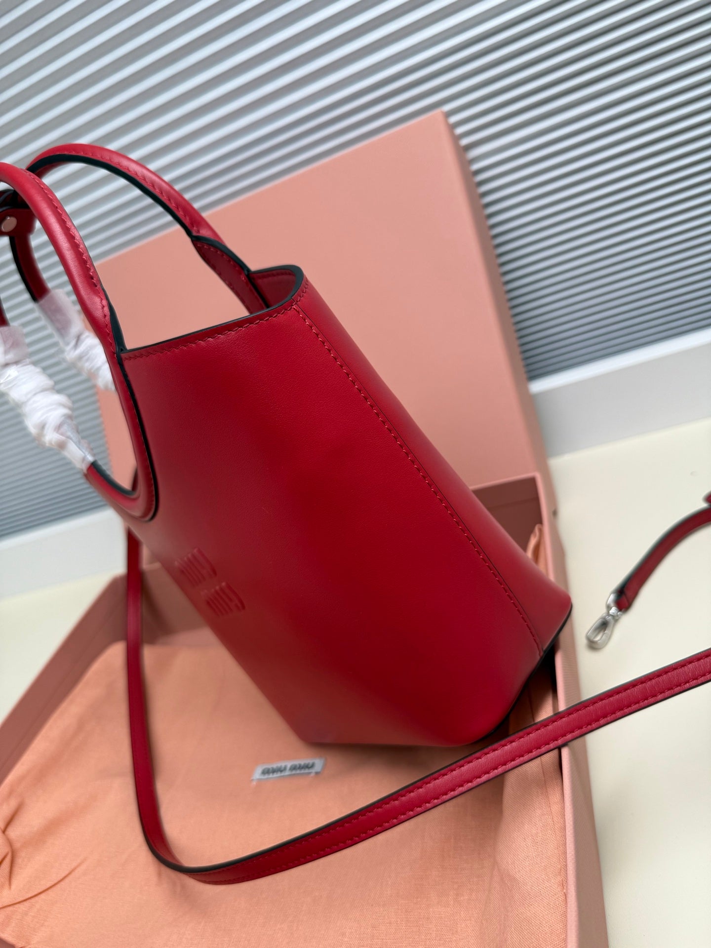 Red leather Miu Miu shoulder bag with curved side and logo patch on front
