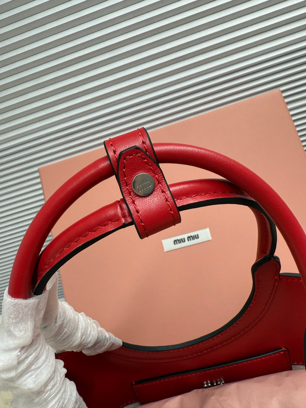 Red leather Miu Miu bag with adjustable strap and top handle detail