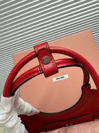 Red leather Miu Miu bag with adjustable strap and top handle detail