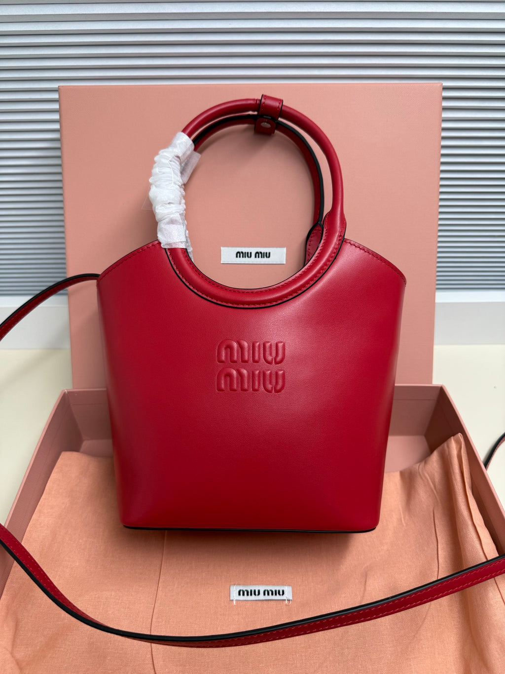 Red leather Miu Miu top-handle bag with embossed logo and fabric-wrapped handle grip