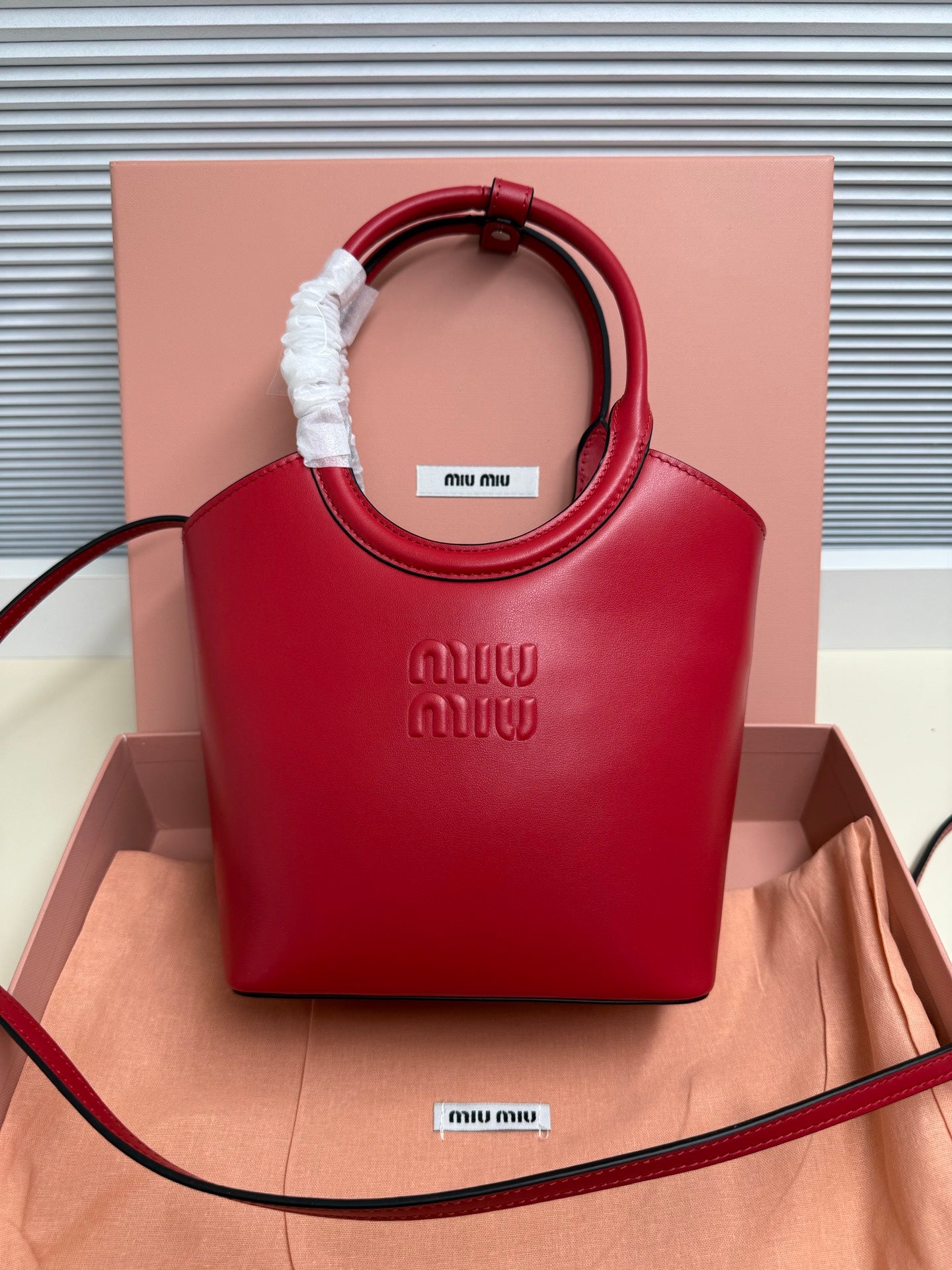 Red leather Miu Miu top-handle bag with embossed logo and fabric-wrapped handle grip