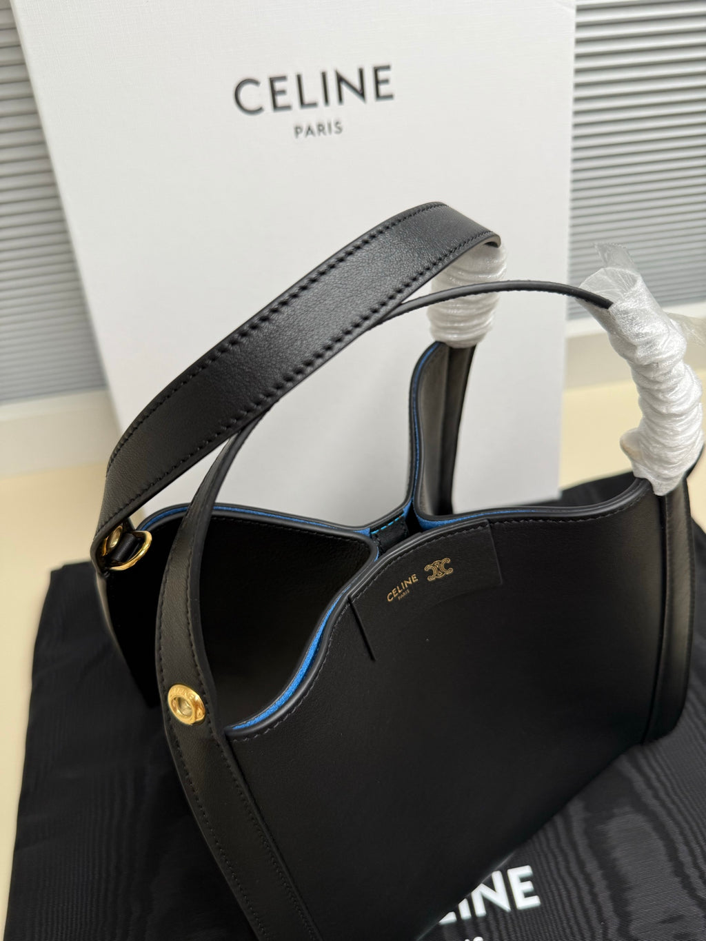 Celine handbag angled view with wide top handle, dark leather and gold-tone clasp hardware