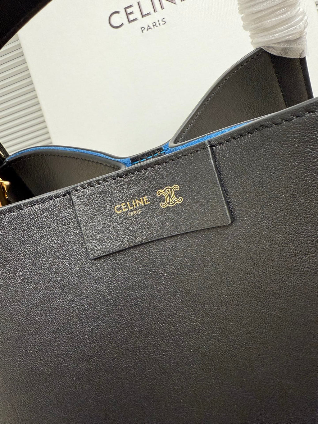 Celine dark leather handbag close-up of front logo patch and blue-lined interior opening