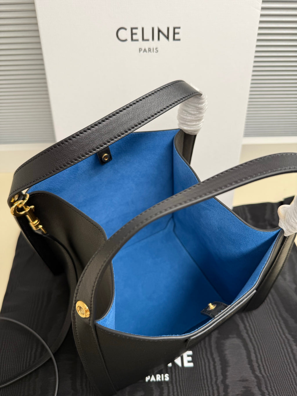 Celine handbag open top with vivid blue lining, dark leather, and gold-tone side hardware