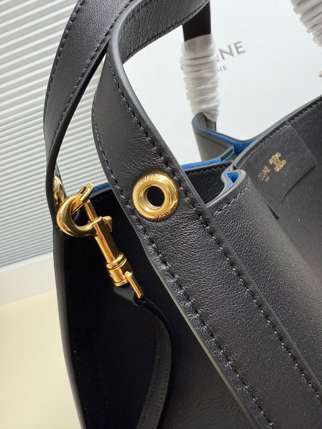 Celine handbag close-up of dark leather strap, gold-tone rings, and decorative hardware