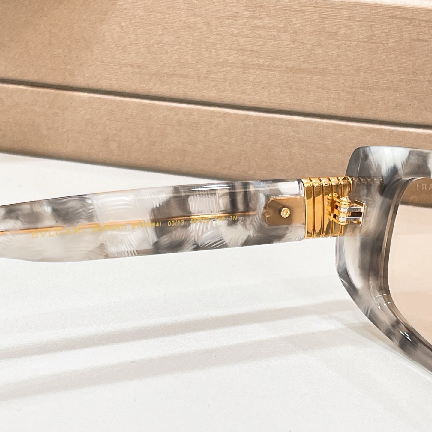 Bvlgari eyeglasses, side view close-up of clear gray frame and gold-tone hinge