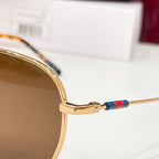 Sunglasses close-up: gold frame with green tinted lens and multicolor temple stripe