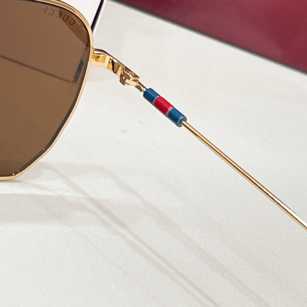 Sunglasses close-up: gold frame with brown tinted lens and multicolor temple stripe