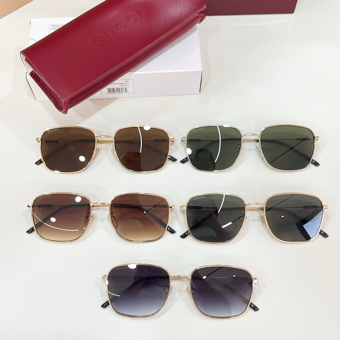 Three pairs of gold-tone aviator sunglasses with dark lenses, shown with red case