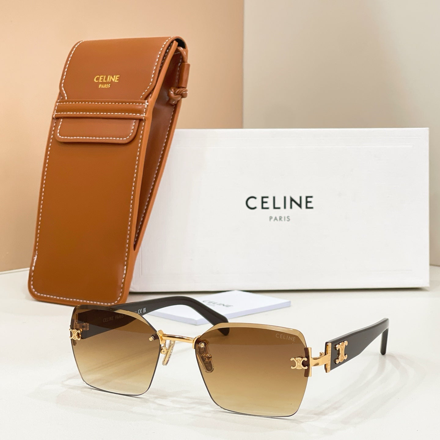 Celine sunglasses with gold frame, amber gradient lenses, and brown leather case.