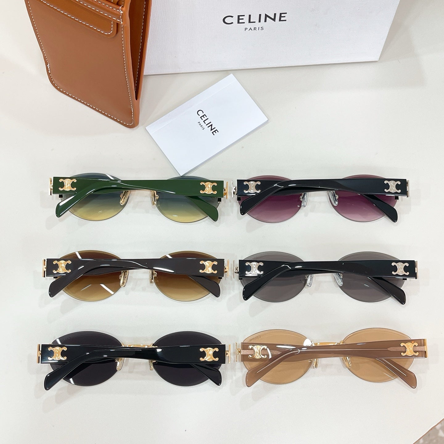 Assorted sunglasses with green, pink, and tan lenses; black frames with gold logo hinges.