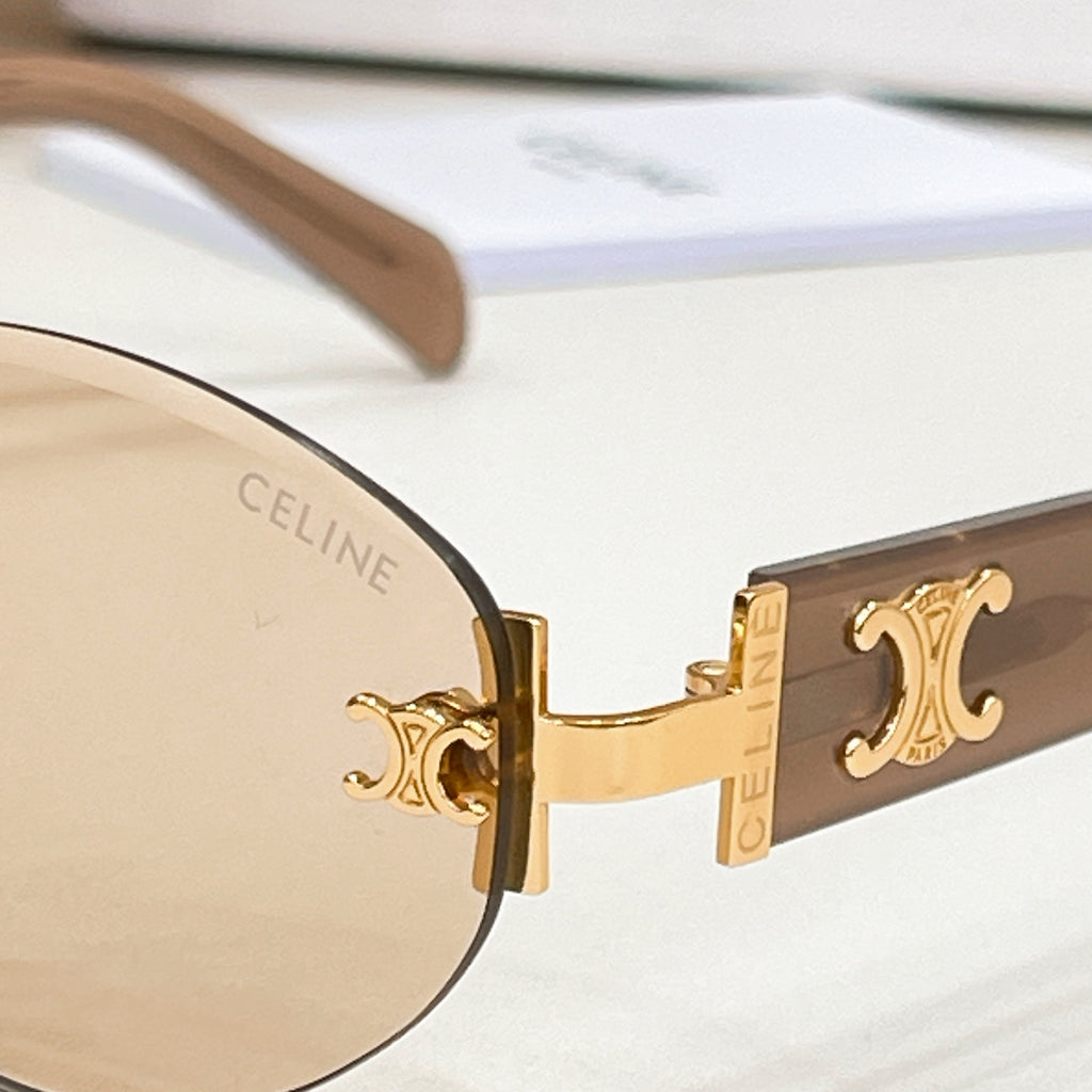 Cat-eye sunglasses close-up: gold hinge and beige lens with logo script on the temple.