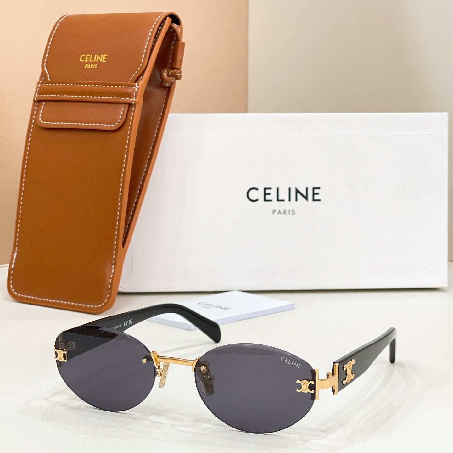Cat-eye sunglasses with gold frame, dark navy lenses, and black temples with gold logo detail.