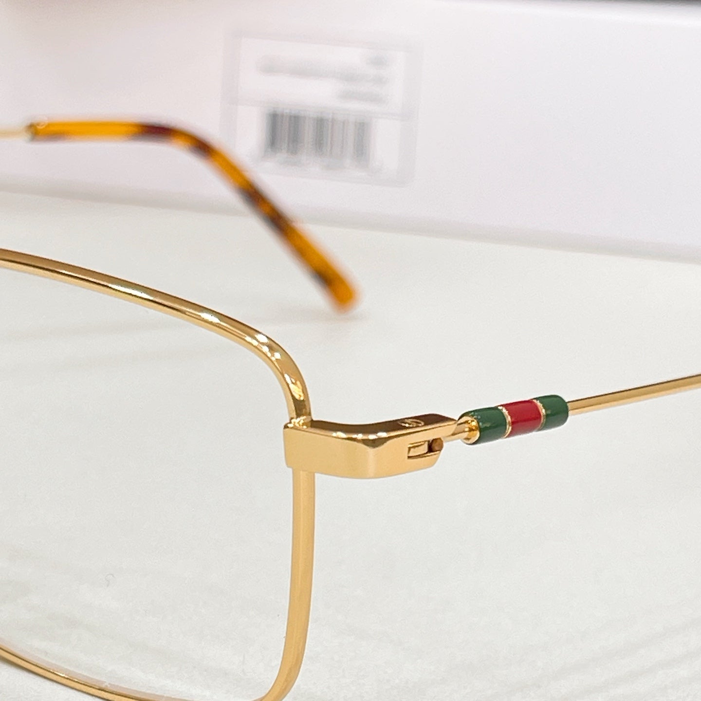 Gold eyeglasses close-up of temple joint with green-red inlay