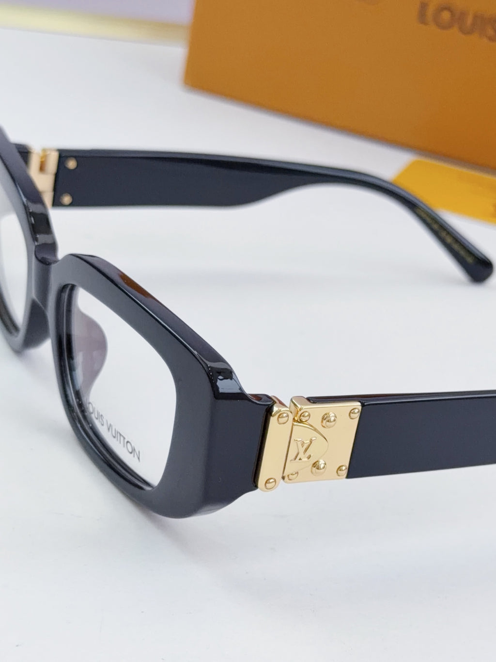 Louis Vuitton eyeglasses close-up: dark frames with gold hinge and logo plate
