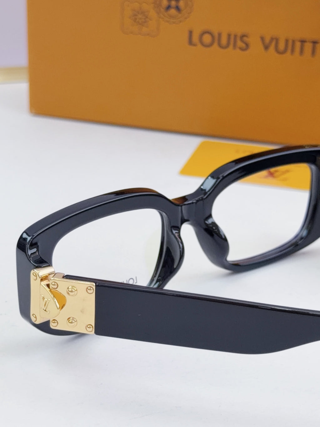 Louis Vuitton eyeglasses close-up: dark frames with gold front logo plate