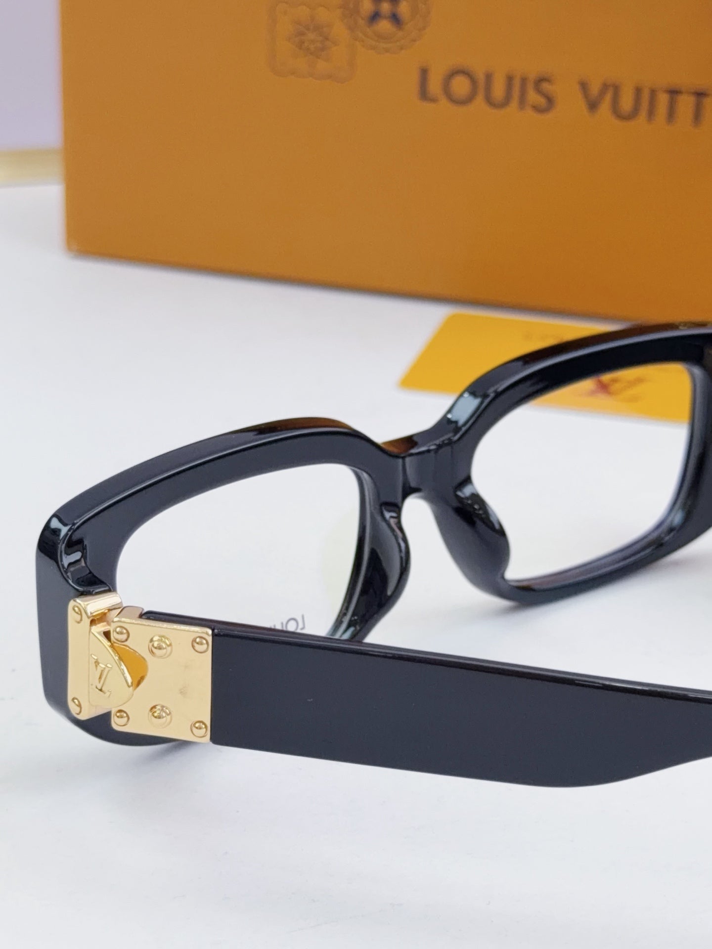 Louis Vuitton eyeglasses close-up: dark frames with gold front logo plate