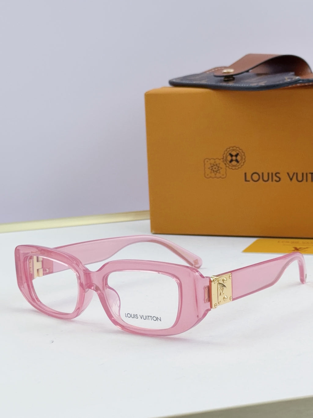 Louis Vuitton eyeglasses with pink frames and gold logo detail at the hinge