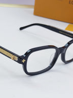 Louis Vuitton glasses close-up with dark frames and gold logo side detail
