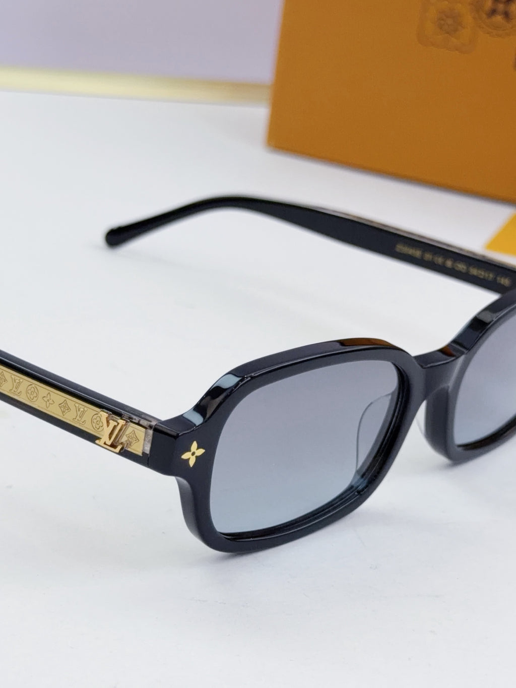 Louis Vuitton glasses close-up with dark frames, gold trim, and star details