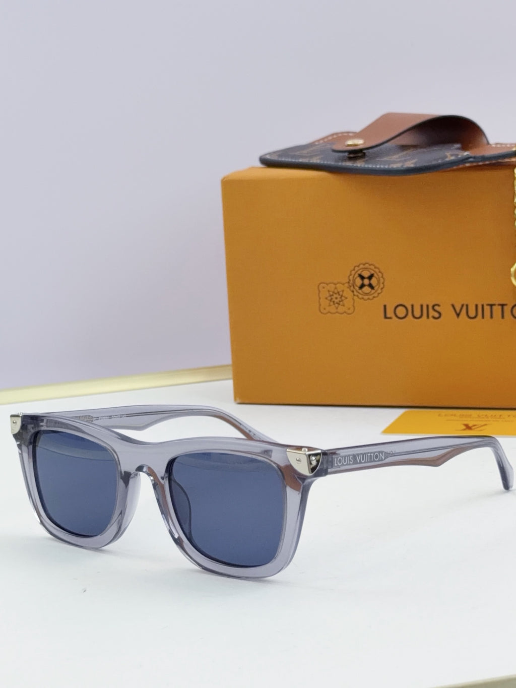 Louis Vuitton sunglasses with light gray frames and blue tinted lenses