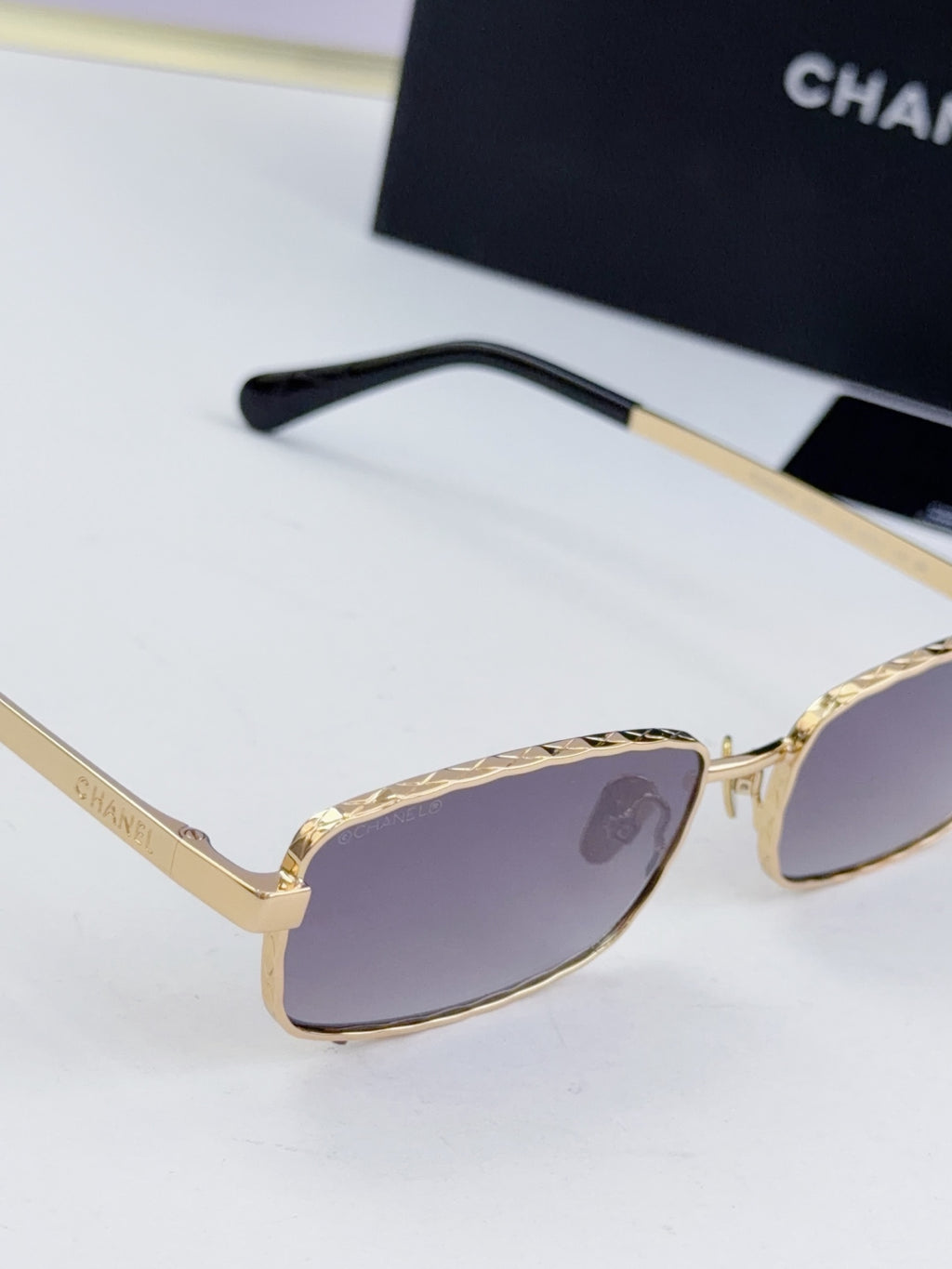 Gold Chanel glasses with purple-tinted lenses and black temple arm