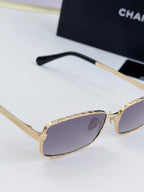 Gold Chanel glasses with purple-tinted lenses and black temple arm