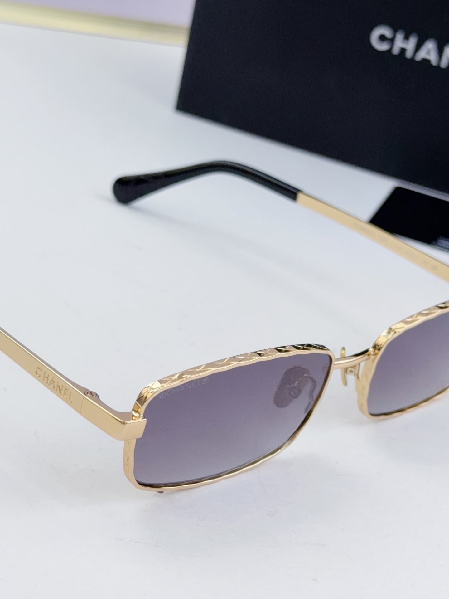 Gold Chanel glasses with purple-tinted lenses and black temple arm