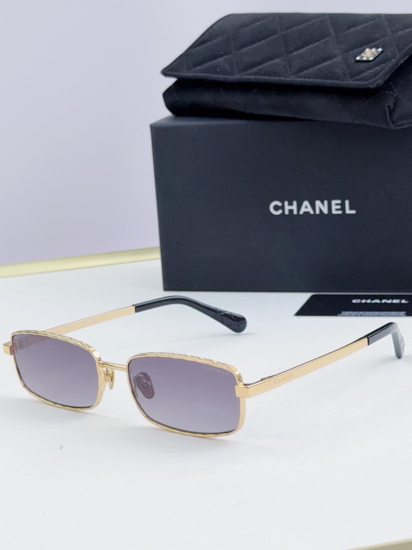 Gold Chanel glasses with rose-tinted lenses and black temple tips