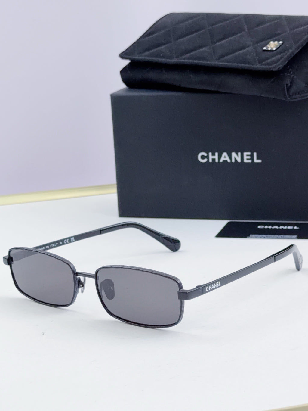 Black Chanel glasses with gray tinted lenses and curved temple arms