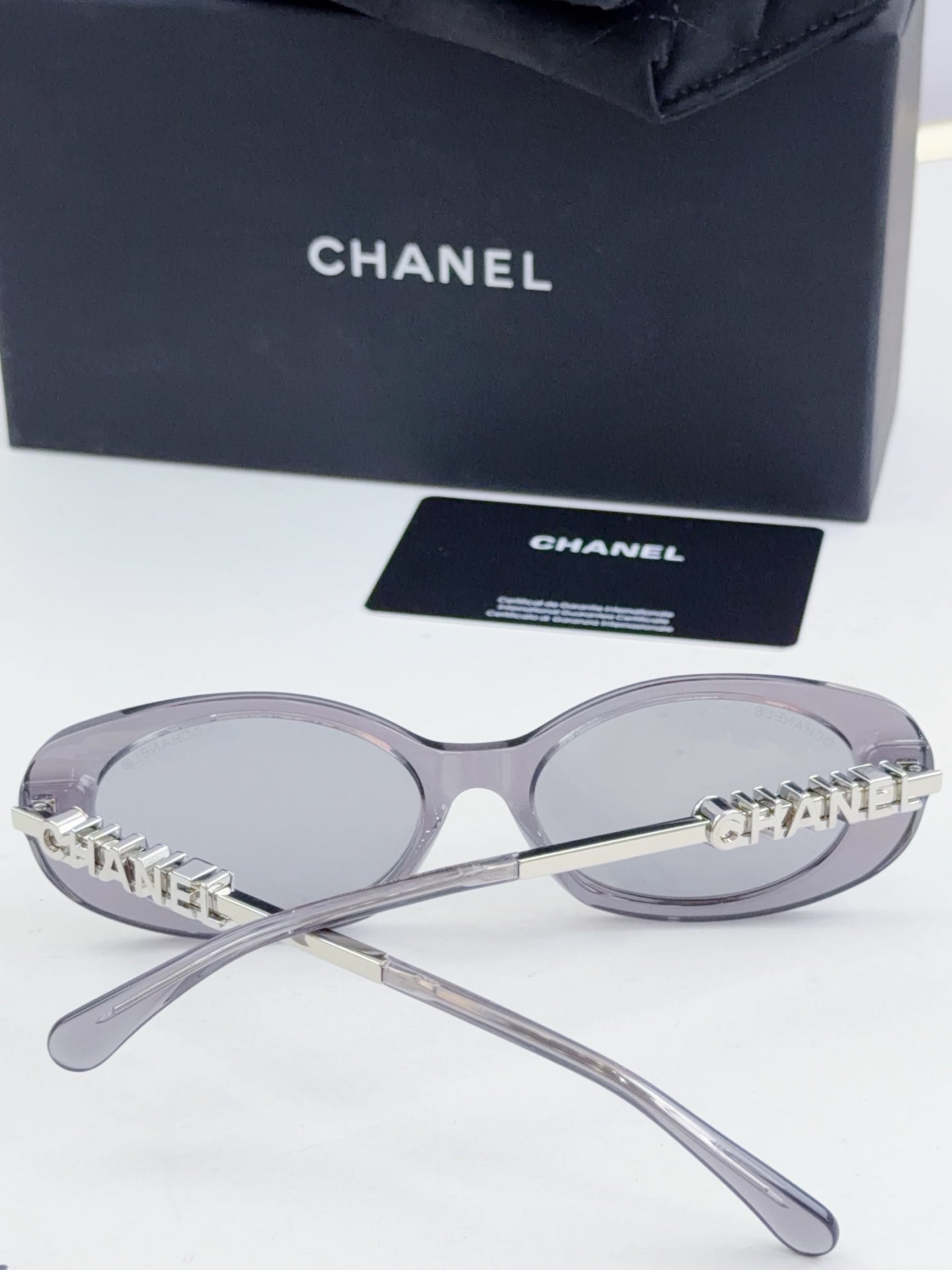 Chanel round sunglasses with clear-gray frames and tinted lenses, metal temple arms.